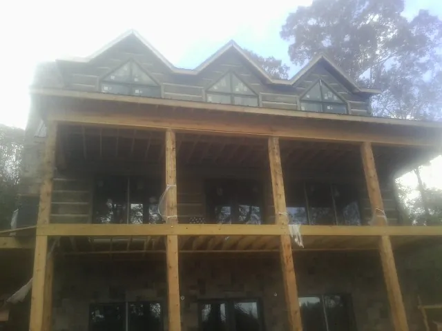 Dormers and porch framing on a large log home under construction — Roof Coating work by our crew in Sand Springs