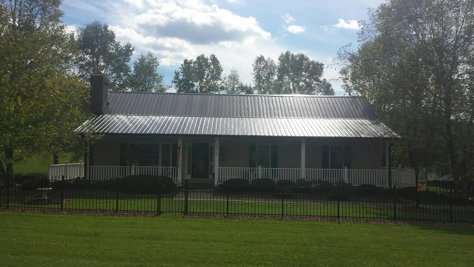 Gray metal roof on a brick ranch with a full width front porch — Gutter Guard Installation work by our crew in Sand Springs